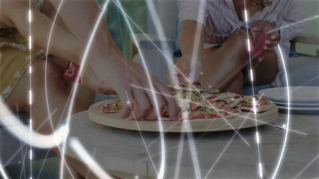 Two women reaching for pizza on wood board, light streaks showing hands picking slices serving food