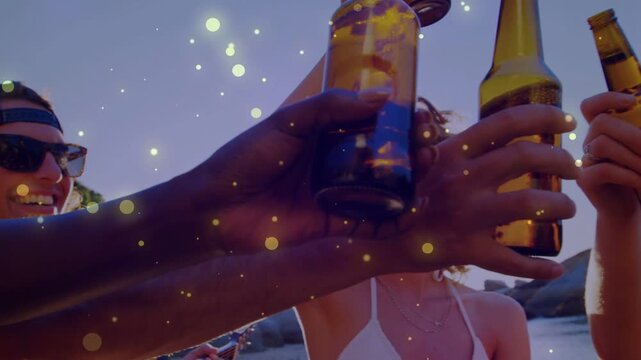 Group toasting beer bottles on beach at dusk guitar strumming particles drifting celebrating social