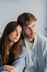 Fototapeta premium Thoughtful young couple sitting close together, sharing a quiet pensive moment in their relationship