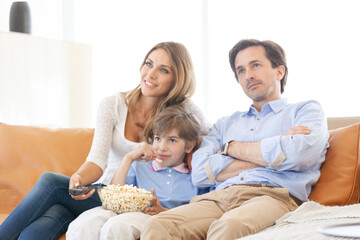 Obraz premium A happy family is sitting on the couch watching TV