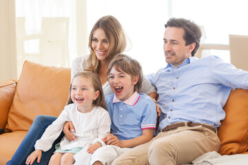 Obraz premium A happy family is sitting on the couch watching TV