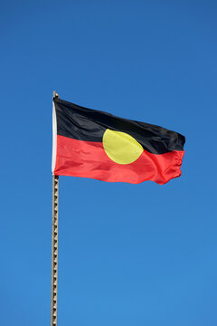 Australian Aboriginal Flag flying prominently against a clear blue sky