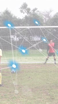 Vertical video: Soccer taker running, trying scoring while AR nodes tracking ball, keeper diving