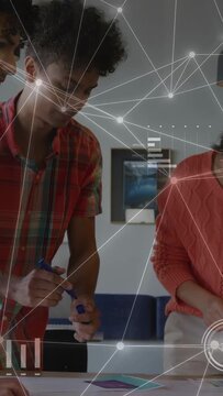Vertical video: Man in plaid placing card, sparking business HUD nodes or gauges or charts, team pla