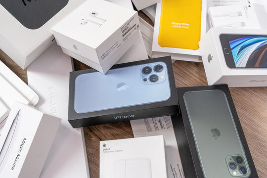 Rostov, Russia - April 04, 2022: Apple iPhone boxes and devices scattered on wooden floor, consumer electronics unboxing, tech haul, product launch excitement.