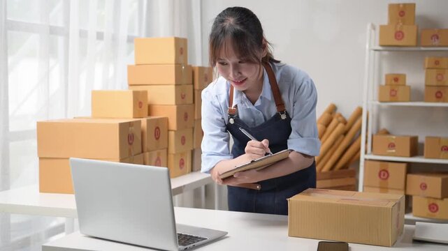 Online seller managing orders on laptop and taking notes