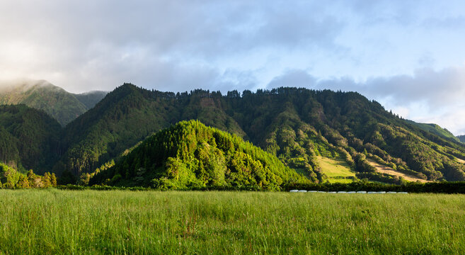 Sete Cidades crater lakes view. Volcanic caldera on Sao Miguel Island. Lush green hills surrounding twin lagoons. Scenic Azores landscape under cloudy sky.