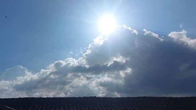 A radiant sun bursts through a dramatic expanse of clouds, casting brilliant light across a vibrant blue sky and illuminating the natural beauty of the ever-changing outdoor atmosphere