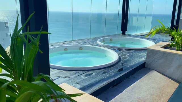 Two Jacuzzi hot tub on a luxury rooftop. Scenic view of the blue ocean horizon at a tropical resort. High-end decor.