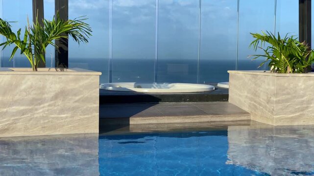 Jacuzzi hot tub and infinity pool on a luxury rooftop. Scenic view of the blue ocean horizon at a tropical resort. High-end decor.