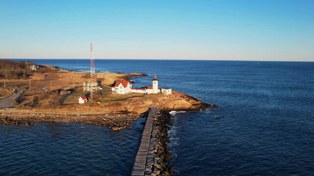 Forward drone fly along the Dog Bar Breakwater toward Eastern Point Lighthouse on rocky Eastern Point viewpoint, Gloucester, Massachusetts, US