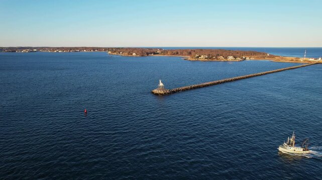 Backward drone orbit near breakwater endpoint Dog Bar Lighthouse with small boat, Gloucester, Massachusetts, US