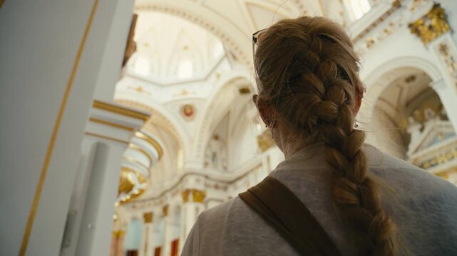 A woman stands inside a beautifully decorated church in Altea, Spain, taking in the elegant architecture and soft light. Calm, reflective atmosphere with a sense of wonder and culture.