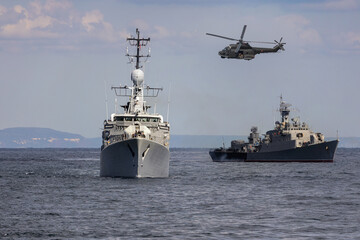 A group of patrol warships accompanied by a helicopter are carrying out a peacekeeping mission in mediterranean sea. Battleships in action. © ValStock