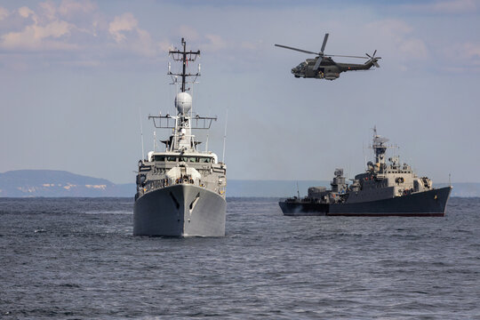 A group of patrol warships accompanied by a helicopter are carrying out a peacekeeping mission in mediterranean sea. Battleships in action.