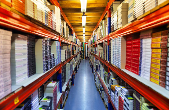 shelving units stacked with numerous books Narrow Aisle in Book Warehouse with High Shelving