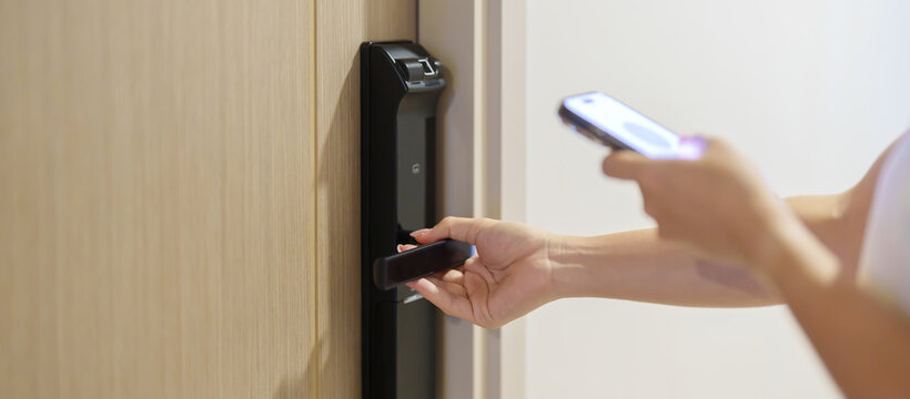 Hand using smartphone for close or Open digital door lock at home or apartment. NFC Technology, Fingerprint scan, keycard, PIN number, smartphone, electrical and contactless lifestyle concepts