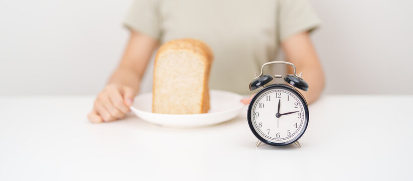 Happy smiling woman with whole wheat bread and alarm clock. concept of intermittent fasting, IF, meal timing, and choosing healthy carbohydrates for a balanced diet and weight loss management