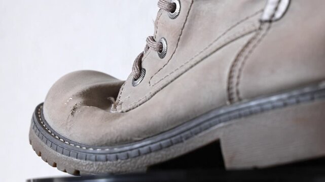 Damaged winter boot falling apart at the seams, worn out shoe