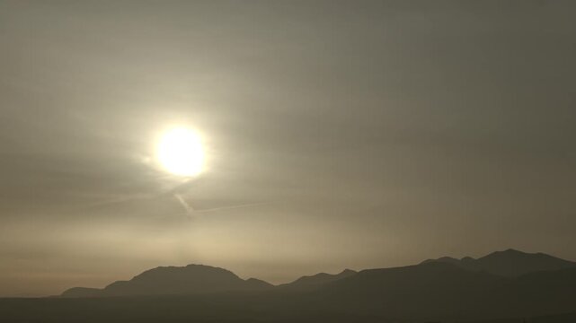 Image of a thick orange haze and haze dust covering the sky above the mountains during sunrise