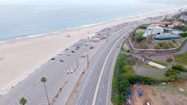 Zuma Beach is a popular surfing destination along the Pacific Coast Highway in Malibu, California at daytime - tilt down aerial flyover
