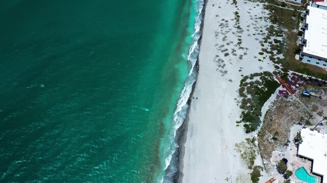 Emerald waters gently lap against a private sandy beach, bordered by urban development. Ideal for real estate or travel promotions.