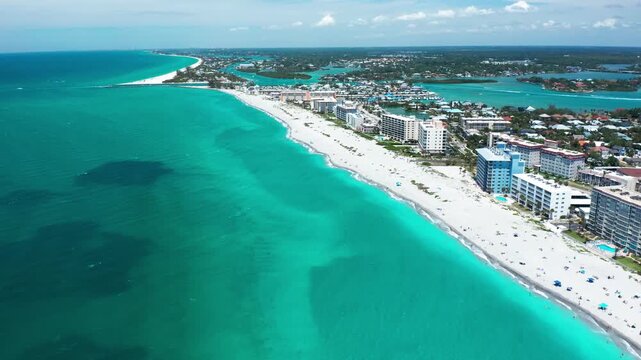 White sand beaches stretch along a vibrant coastline with buildings overlooking the turquoise sea. Ideal for travel and real estate content.