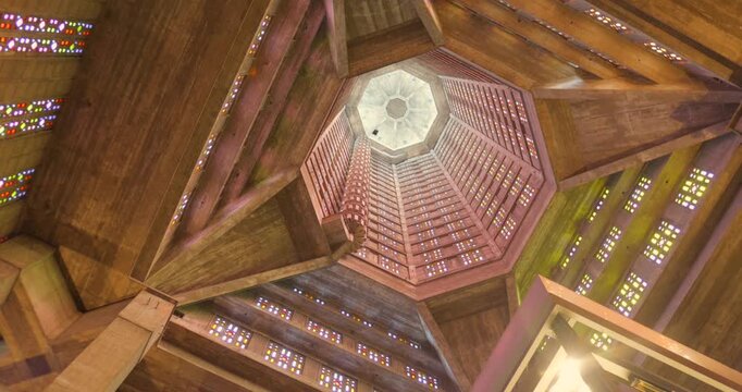 Upward view inside St Joseph's Church octagonal tower in Le Havre, France. Post-WWII UNESCO architectural masterpiece rising 107 meters with colorful stained glass windows.