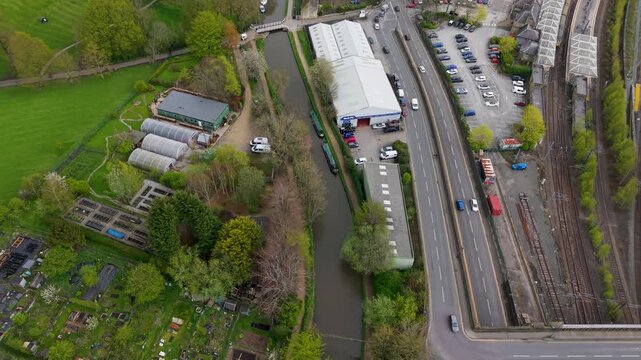 A drone tracks the curves of the Leeds and Liverpool Canal through Skipton, with Aireville Park allotments to the left, the A6069 Broughton Road and railway sidings to the right. Spring aerial footage