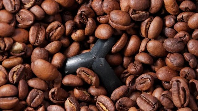 Top-down close-up of coffee beans grinding inside a coffee grinder, capturing rich texture, motion, and aromatic detail in a cinematic macro shot.