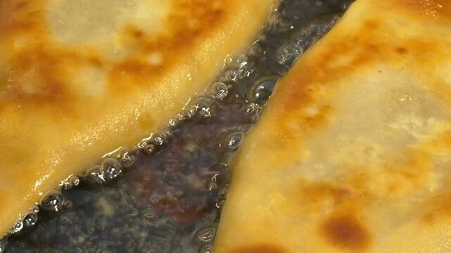 Fast food meat-filled pastries are fried in boiling oil