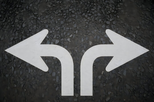 White painted left and right directional arrows on black asphalt road