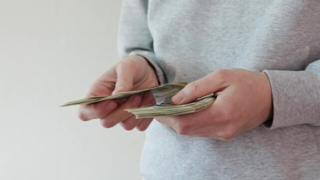 People counting and flipping stack of US dollar banknotes in hands, cash money close up