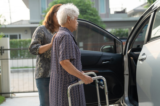 Caregiver help Asian elderly woman disability patient get in her car.
