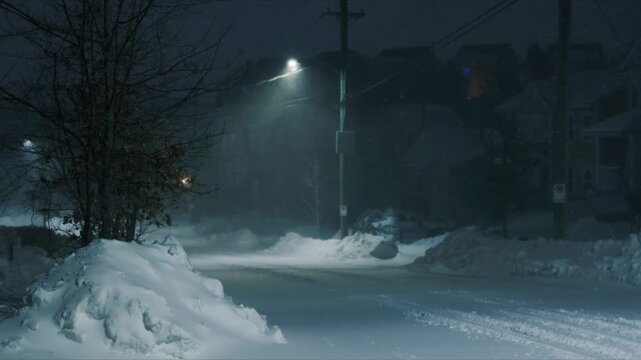 Dramatic nighttime footage of a powerful blizzard raging in Beechville suburb Halifax. Strong winds and heavy snow create massive snowdrifts that bury streets and sidewalks, streetlights glow weakly
