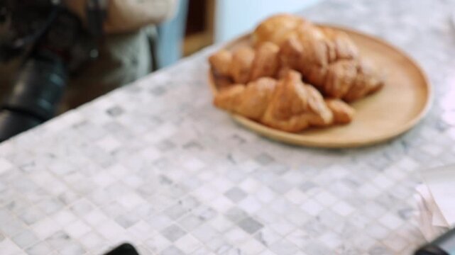Senior entrepreneur cafe owner barista hold POS machine to customer, Asian female in apron welcome warmly in counter, croissants and glassware background, retired elderly woman start small business