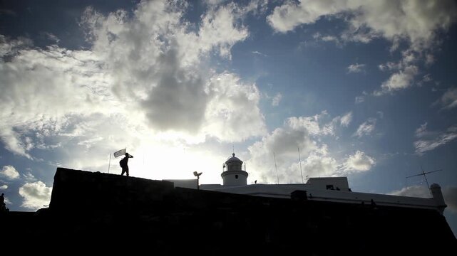 Man Standing by Uruguay Flag at Sunset in Fortaleza del Cerro Montevideo - 4K
