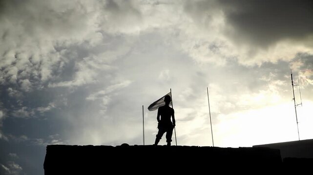 Cinematic Silhouette of a Man Overlooking the City Skyline from El Cerro Fortress with the National Flag Waving - 4K