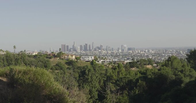 Cinematic daytime 4K 10-bit footage captured from a scenic overlook in Griffith Park featuring a wide, distant view of the downtown Los Angeles skyline.
