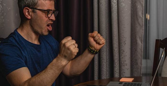 Angry freelancer reacting to problem while working on laptop at night