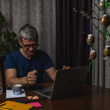 Angry freelancer reacting to problem while working on laptop at home