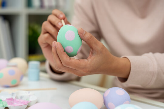 close up hand painting and decorating colorful egg at home on easter day
