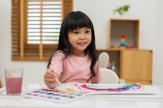 happy preschool child girl painting with watercolor on paper