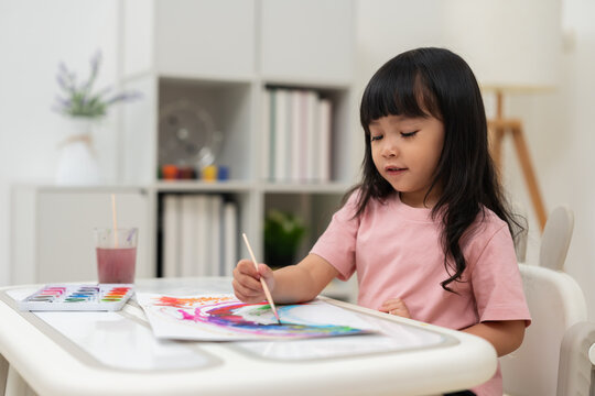 preschool child girl painting on paper with watercolor in pan