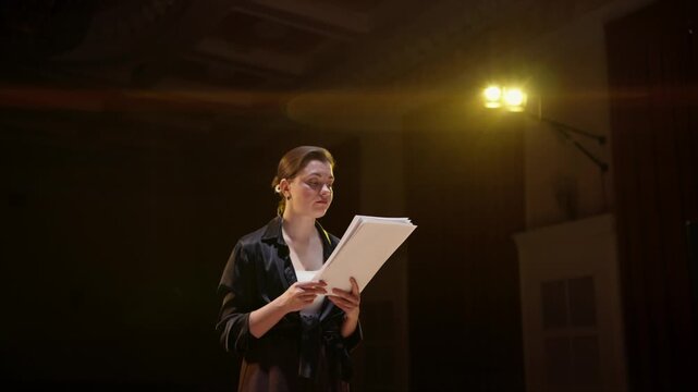 Focused theatre rehearsal with actors studying scripts under warm stage lighting, capturing concentration, collaboration, and performance preparation on an indoor stage