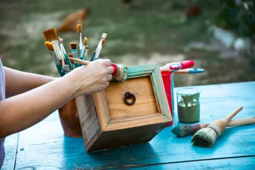 Fototapete Alte Türen Painting a wooden furniture outdoors, an eco-friendly re-use business.  © erika8213