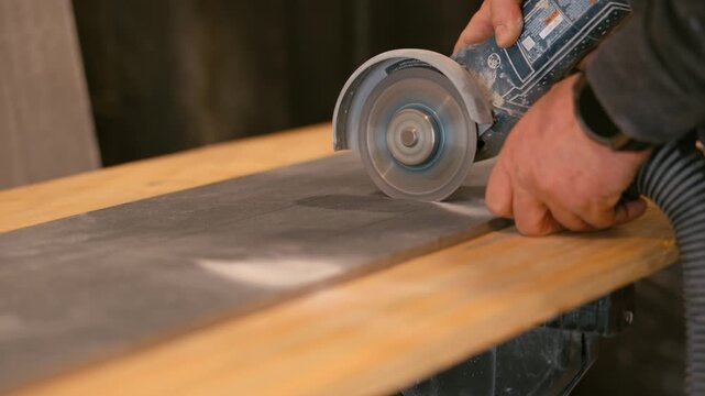 Worker cutting grey tile with electric angle grinder. Close up of construction tool in use during renovation and installation work.