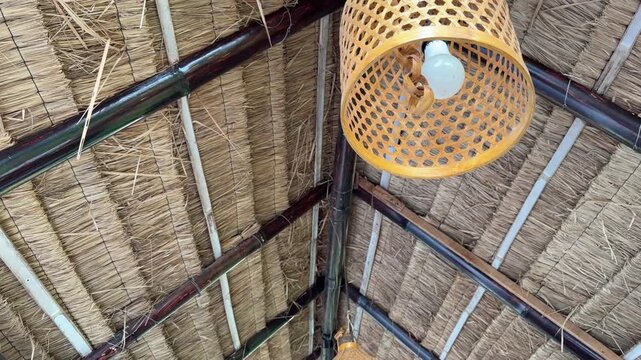 Thatched roof with bamboo beams and woven lanterns. Lanterns hang suspended, casting soft, warm glow. Structure suggests tropical, rustic, or beachside ambiance