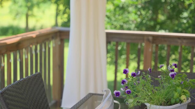A graceful tilt-up shot starting from white rhinestone-encrusted heels and purple flowers on a glass table, revealing a stunning lace wedding gown hanging against a lush summer background.