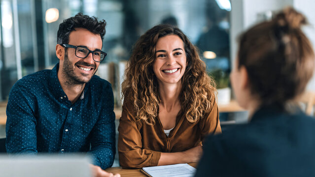 Professional immigration attorney consulting a happy couple holding passports in modern office in the USA. Smiling lawyer assisting clients with green card and visa application process, legal advice. 
